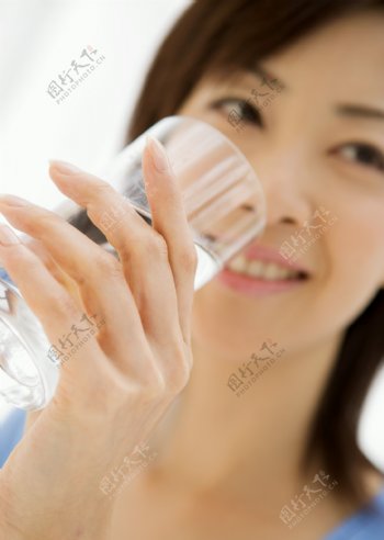 女性用透明的玻璃杯子喝水图片