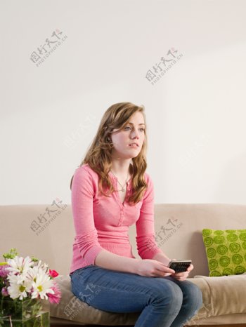 坐在沙发上玩手机的外国女人图片