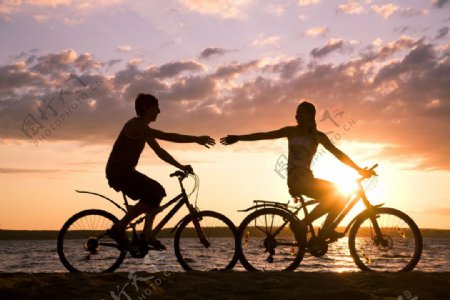 夕阳下海边骑自行车的情侣图片