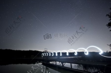 白色霓虹灯点亮水的木制码头高于体温在星夜的天空