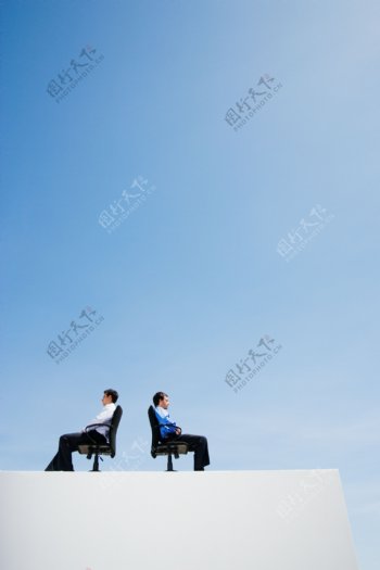 坐在沙发上背靠背的两个外国男人图片