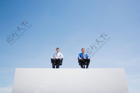 坐在沙发上看前方的两个男人图片