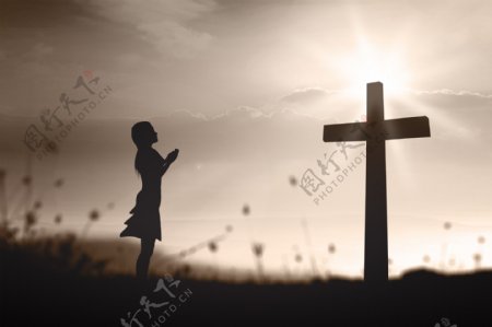 朝十字架祈祷的女孩图片
