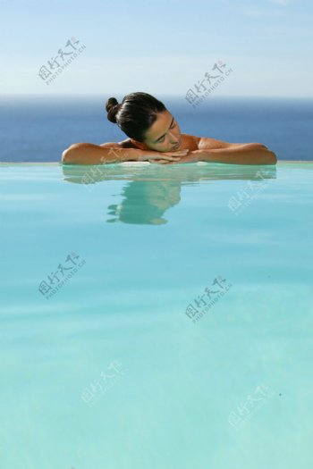趴在泳池边休息的女人图片