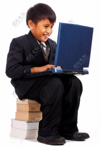 男孩用他的电脑坐在一堆书