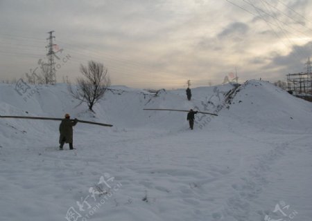黄昏雪后工作的电力工人图片