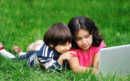 绿草地上笔记本电脑上网娱乐的孩子图片