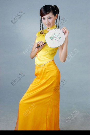 拿扇子的黄旗袍美女图片