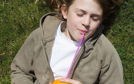 草地上喝橘子汁的孩子图片