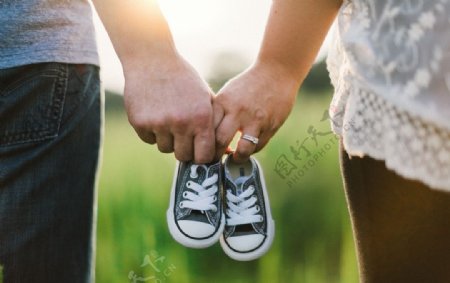 夫妇牵手拿着婴儿鞋