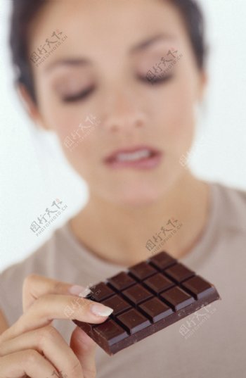 拿着巧克力咬嘴唇的女孩图片图片
