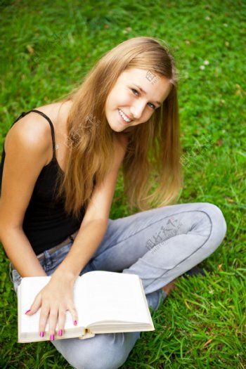 坐在草地上拿着书的美女图片