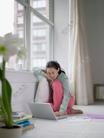 窗台边坐着玩电脑的女人图片