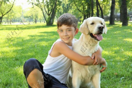 抱着狗狗在草地上的男孩图片