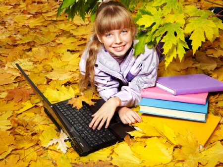 趴在枫叶地上玩电脑的女孩图片