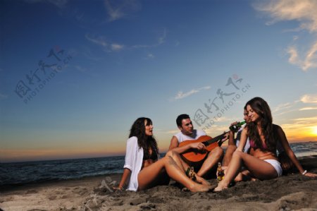 坐在沙滩上唱歌的青年图片