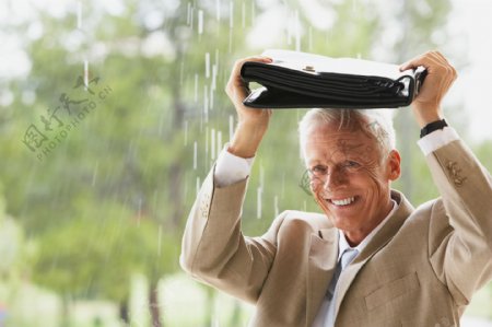 用公文办遮雨的外国老年商务男性图片