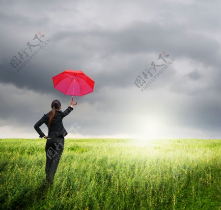 草地上打伞的职业女性图片