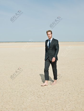 光着脚丫在沙漠中行走的外国商业男人图片