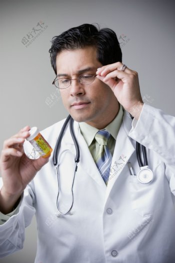 戴着眼镜查看药物的医生图片