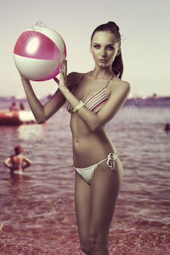 沙滩上拿着皮球的美女图片