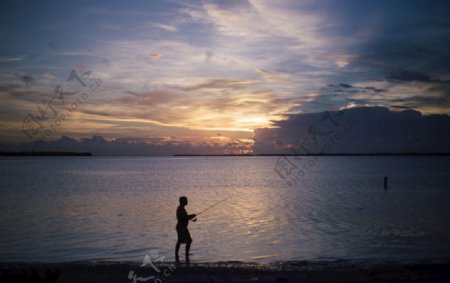 夕阳下海边钓鱼的男人